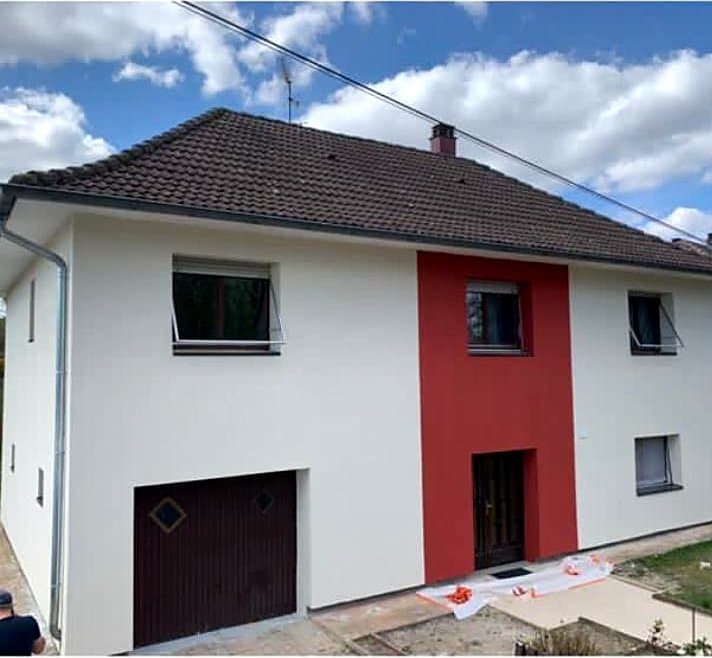Après : La même maison après isolation par l'extérieur : enduit blanc et bande verticale rouge sur l'entrée