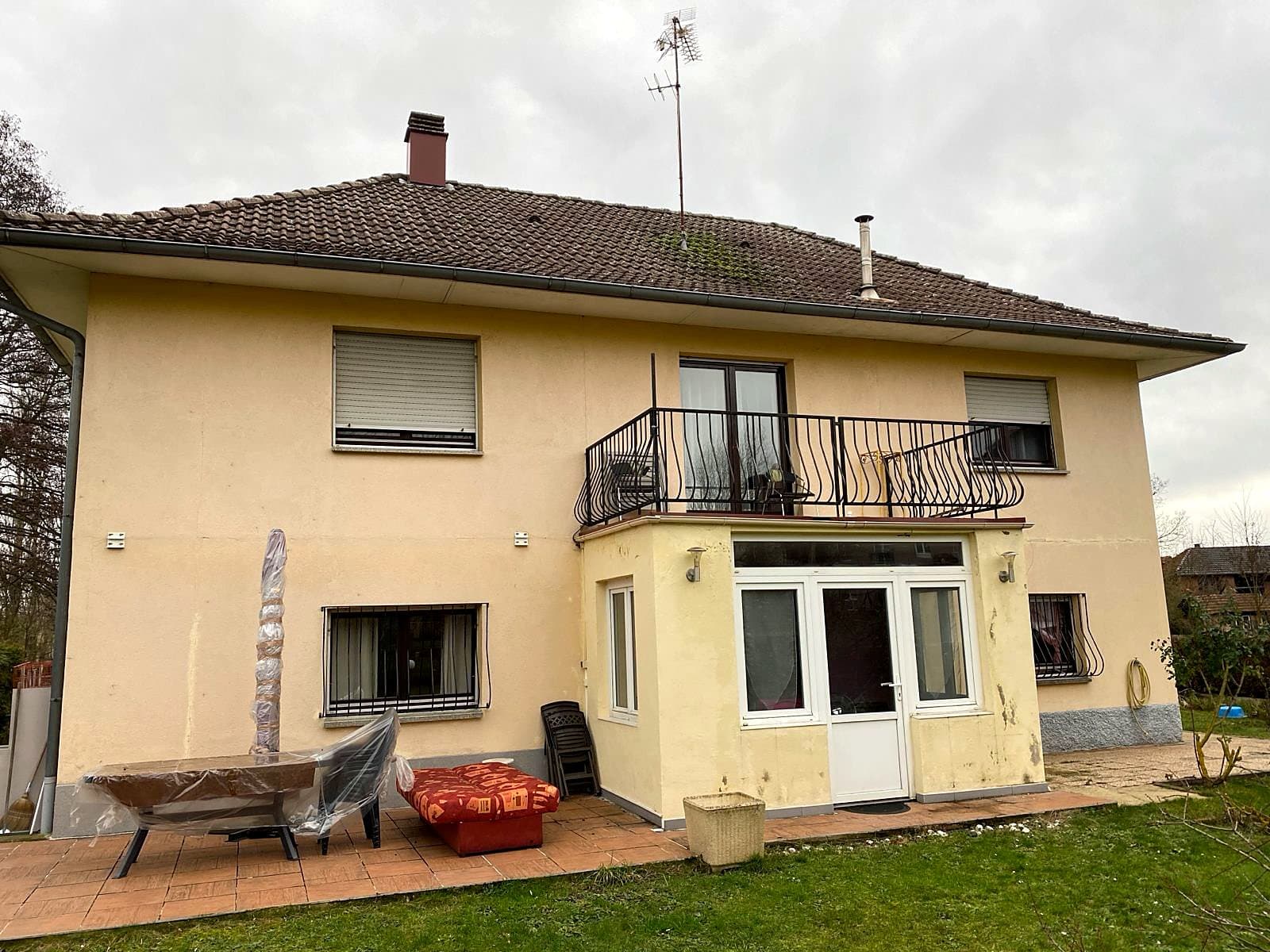 Avant : Façade arrière avec balcon et véranda, enduit jaune écaillé avant travaux