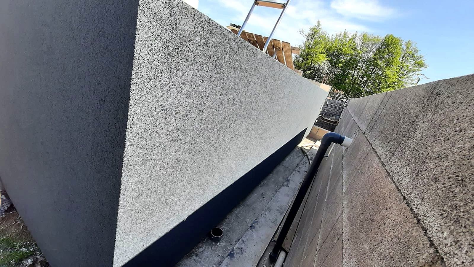 Détail de l'enduit de finition gris sur un mur isolé, au ras du sol