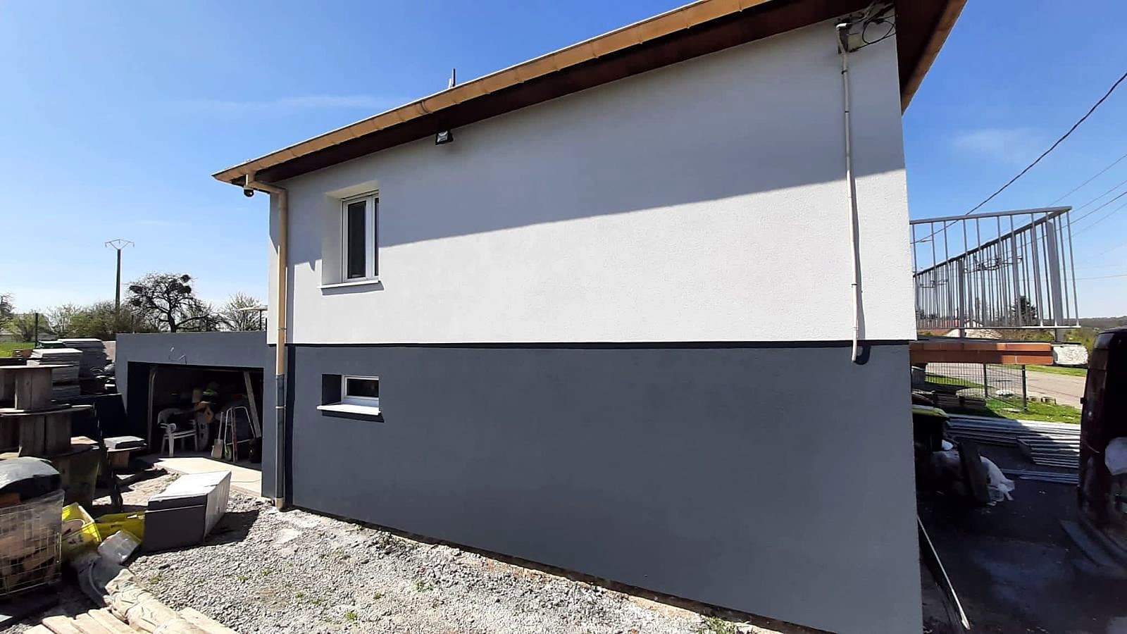 Pignon isolé par l'extérieur : enduit clair en partie haute, soubassement gris anthracite