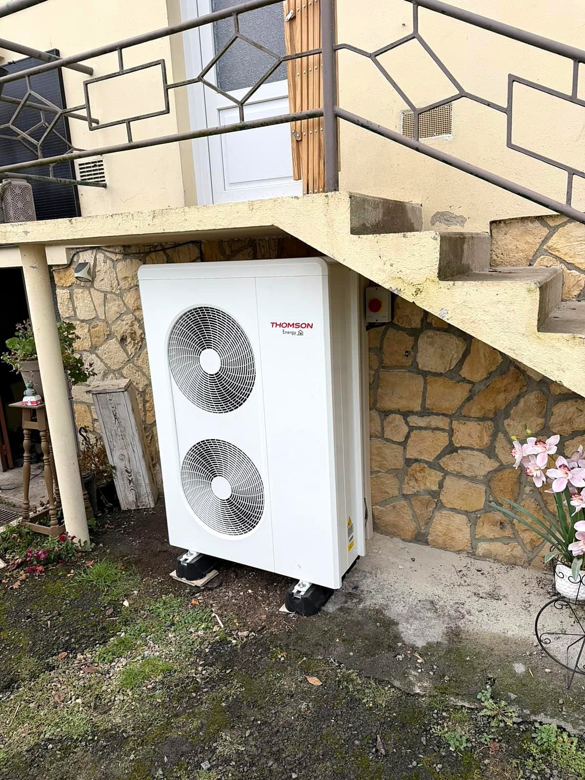 Unité extérieure de pompe à chaleur installée sous un escalier extérieur